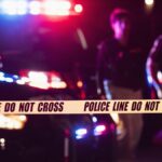 Two police officers behind crime scene tape