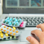 Pills, blister packs and medical bottles in front of laptop,internet shopping