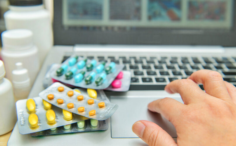 Pills, blister packs and medical bottles in front of laptop,internet shopping